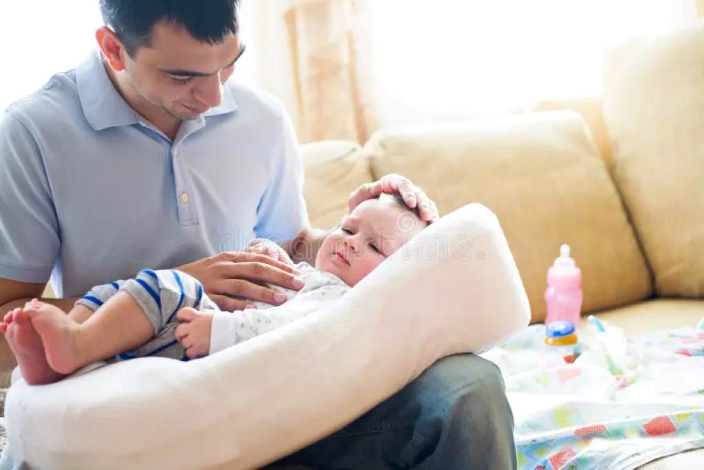 Happy family in nursery, dad using versatile feeding prop for bottle time with smiling infant.