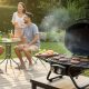 Compact gas grill on small wooden deck with burgers cooking and friends chatting nearby