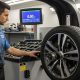 Mechanic inspecting tire balance on professional wheel balancing machine
