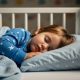Toddler sleeping peacefully on appropriately sized pillow in bed with safety rails