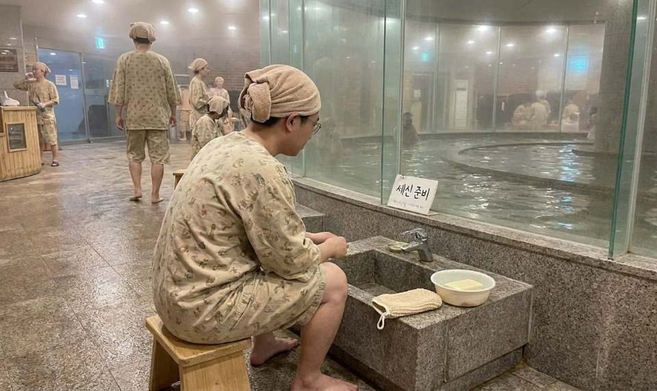 Person preparing for a Korean body scrub at a traditional jjimjilbang spa