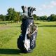 Well-organized golf bag loaded with essential accessories including a towel clip, rangefinder, and divot tools on a sunny fairway