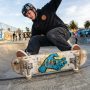 Skater landing a trick on a worn Santa Cruz deck at a California skatepark.