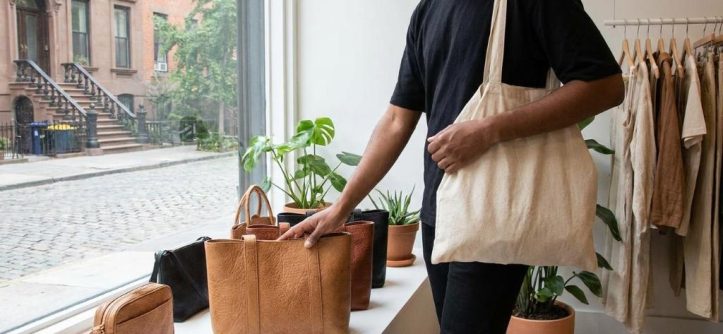 Shopper examining plant-based leather coat in modern New York designer showroom.