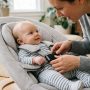 Secure baby bouncer resting on a flat floor in a living room.